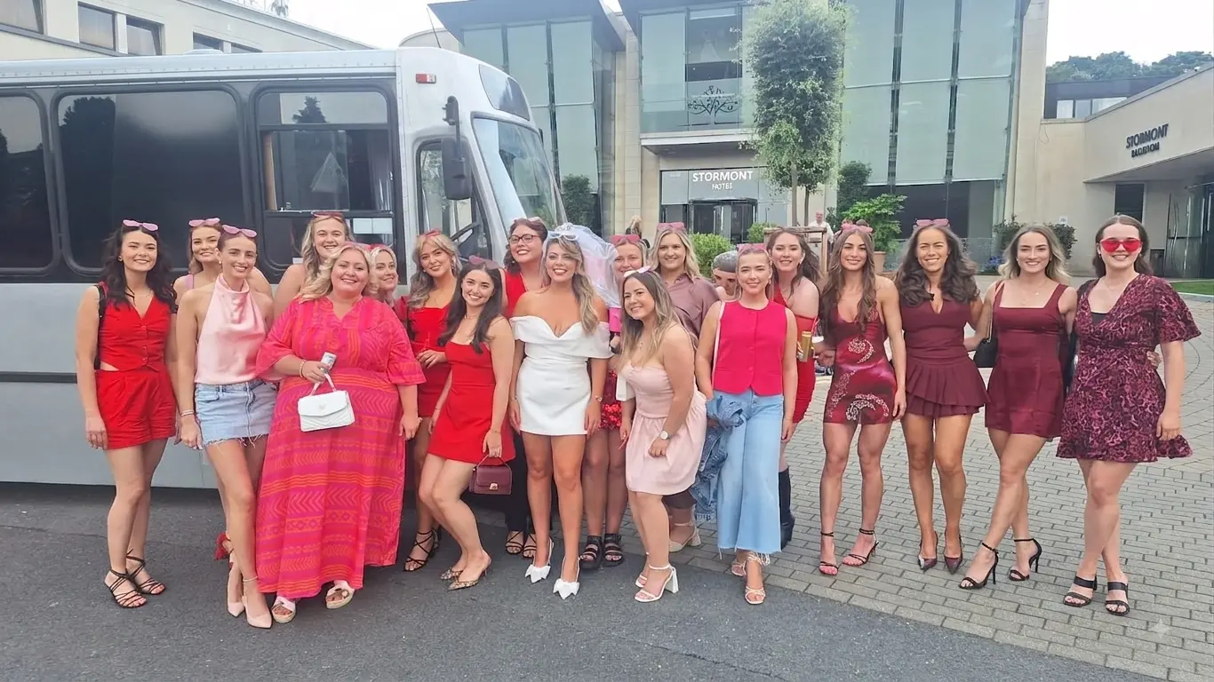 Hen party group in red and pink outside the Stormont Hotel beside the party bus
